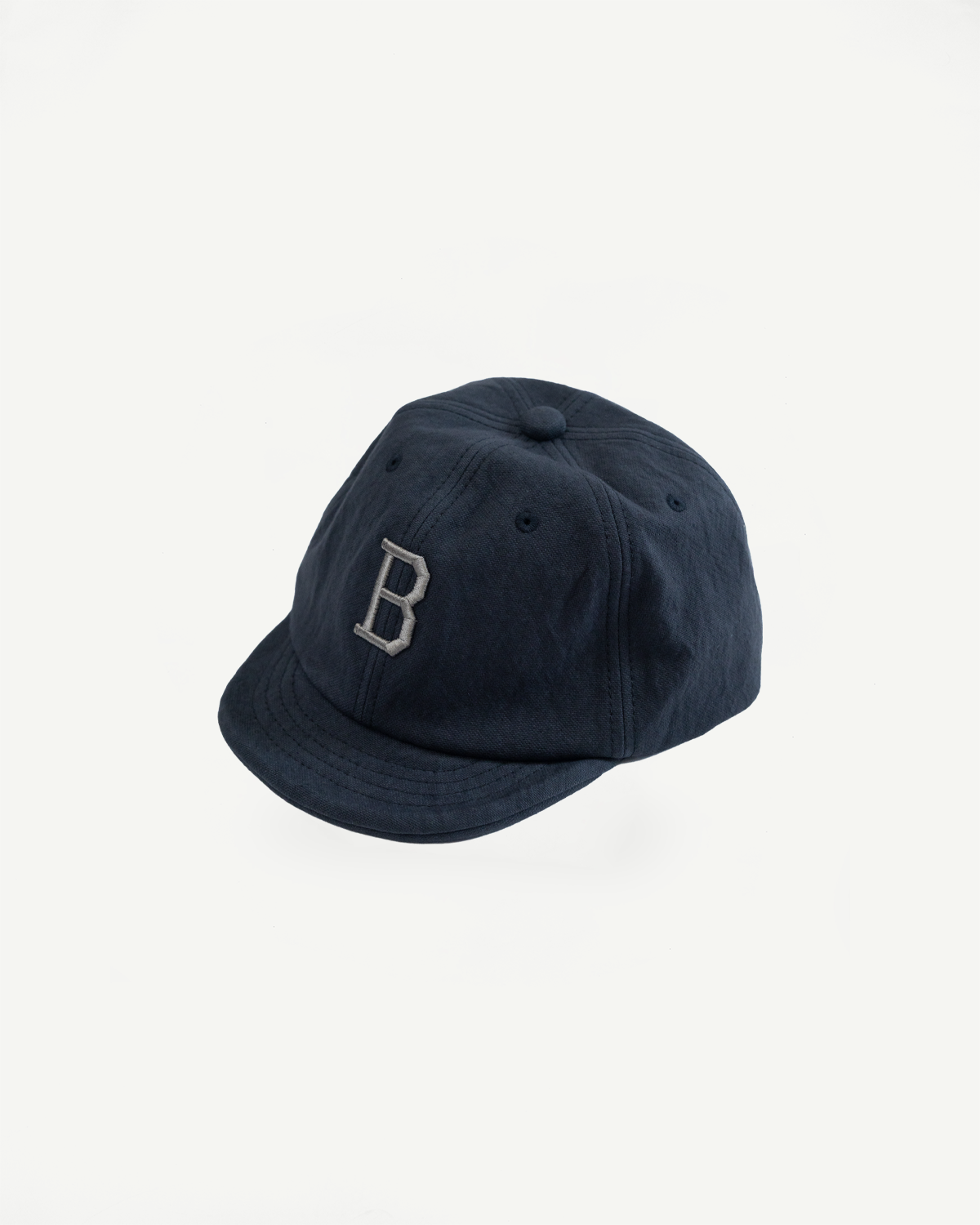 Front view of a navy blue baseball cap with a white letter B embroidery on a white background.
