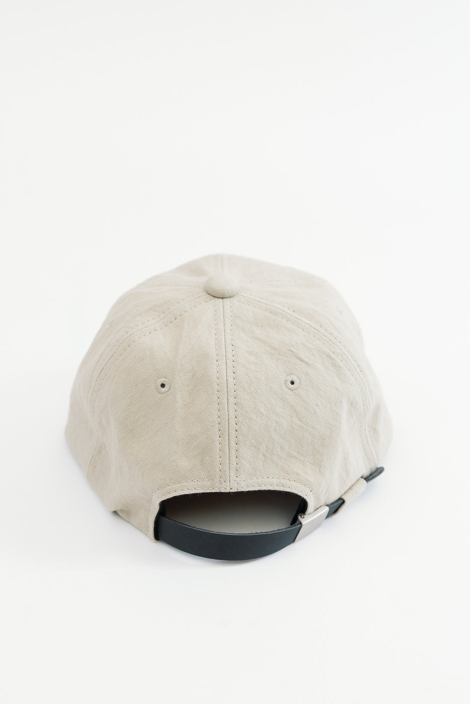 Back view close-up of a beige cotton baseball cap showing the adjustable strap and eyelets.