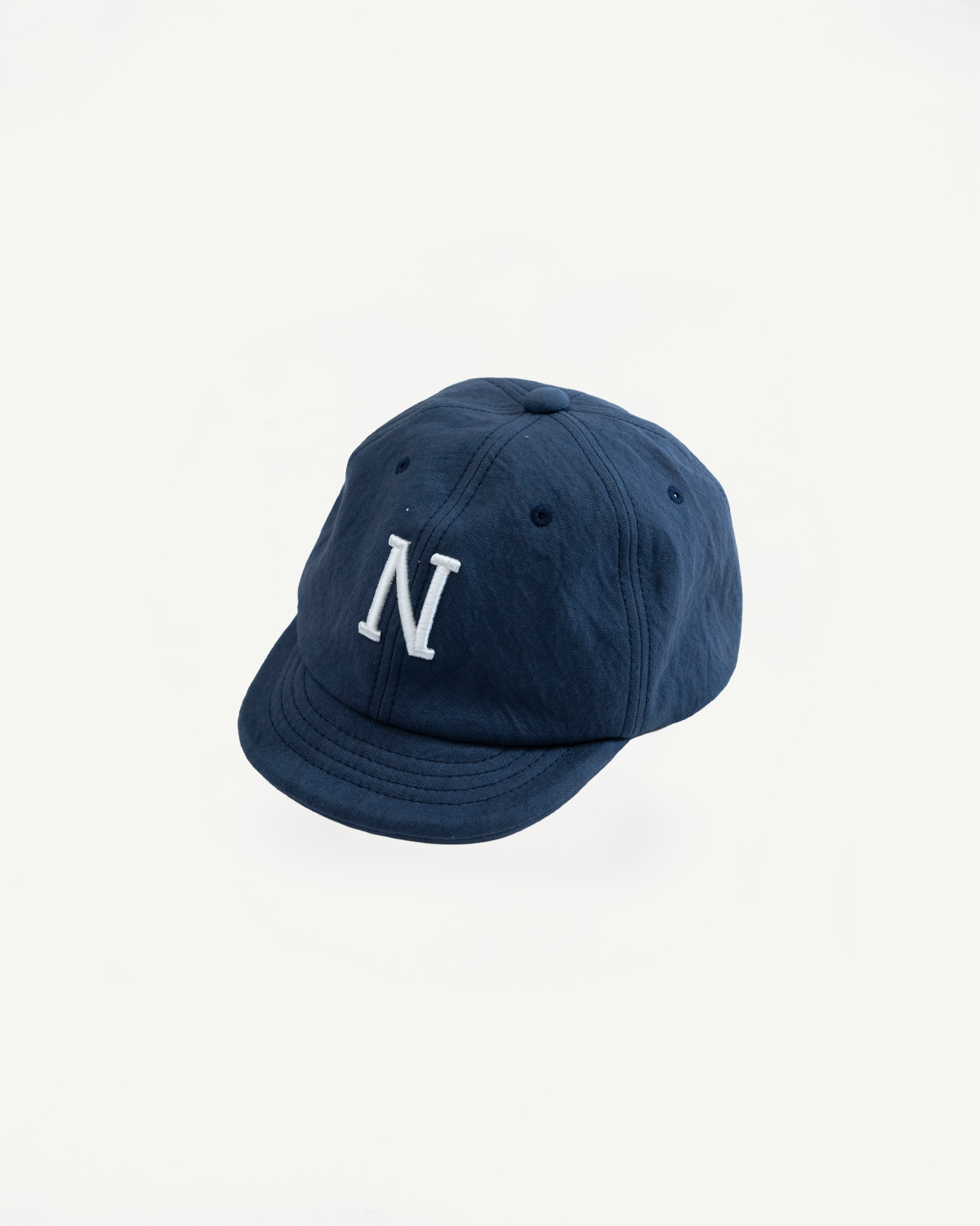 Front view close-up of a navy blue cotton baseball cap with a white embroidered letter N.