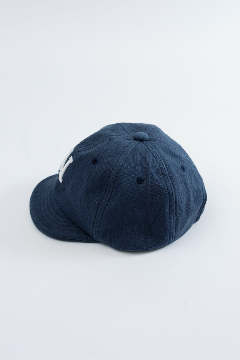 Side view of a navy blue cotton baseball cap on a white background.