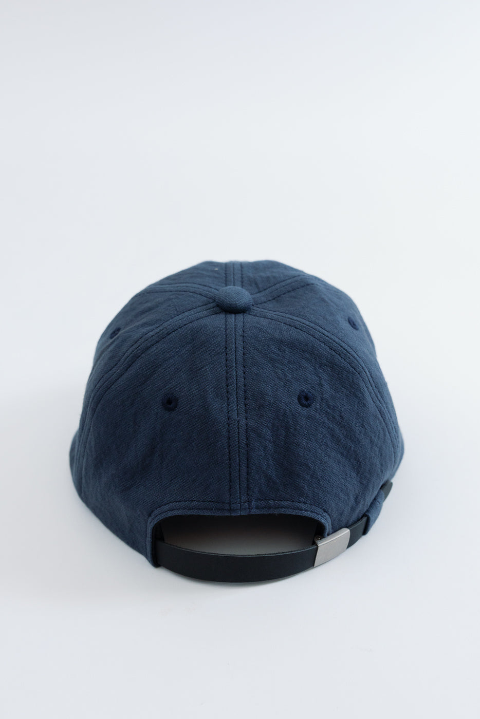 Back view close-up of a navy blue cotton twill baseball cap with adjustable strap.