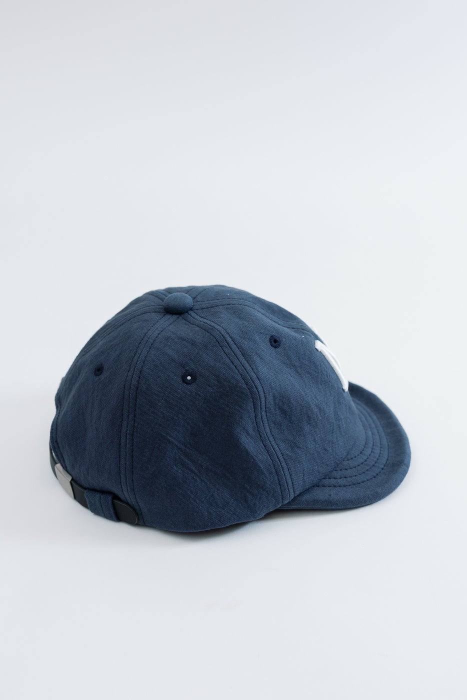 Side view close-up of a navy blue cotton baseball cap showing fabric texture and stitching.