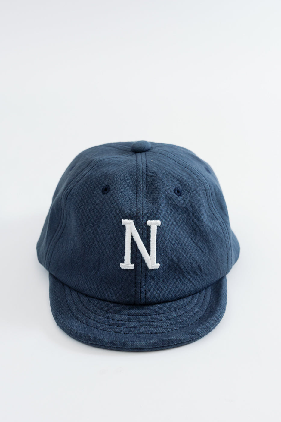 Front view of a navy blue fabric baseball cap featuring a white embroidered letter N.