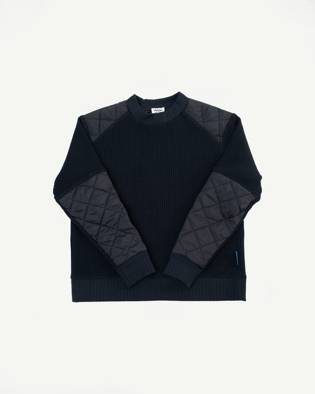 Front flat lay of a navy ribbed sweater with quilted shoulder and sleeve panels.