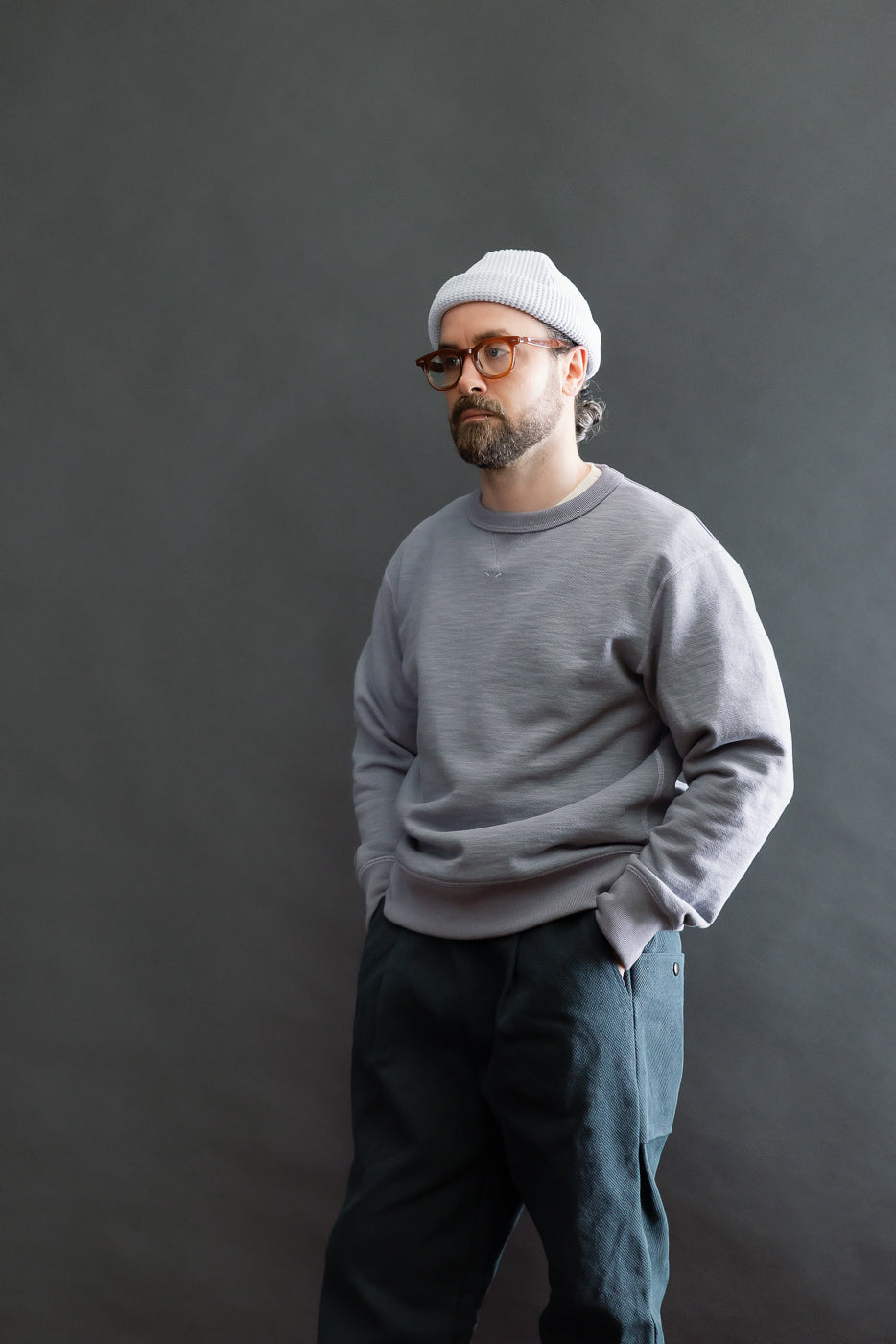 A man models the JM7292 - GG Sweat Crewneck, showcasing its textured weave and relaxed fit. Styled with dark trousers, he highlights the sweatshirt's vintage-inspired ribbing and casual, structured drape.