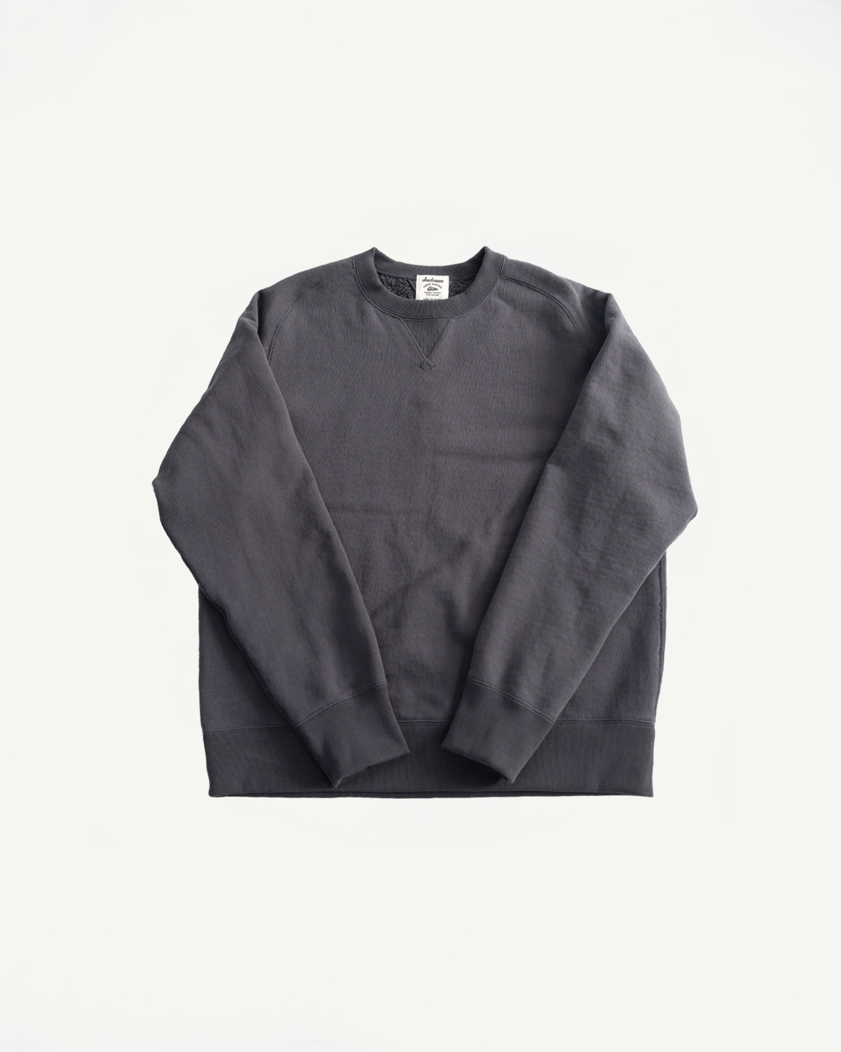 Flat lay front view of Jackman Big Loop Crewneck in ink black, showing cuffed sleeves and V-stitch collar detail