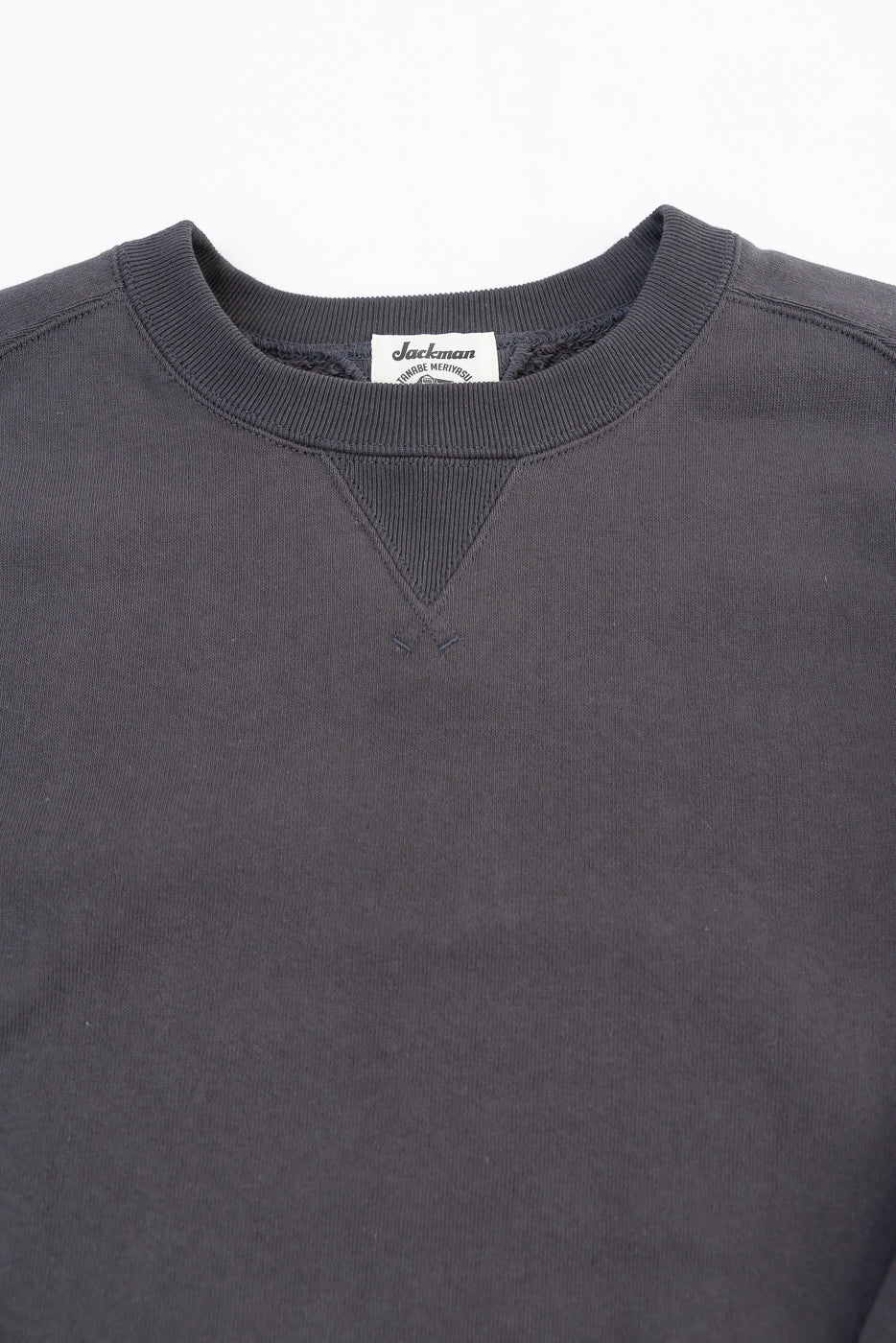 Close-up of the front neckline and Jackman tag of a charcoal grey crewneck sweatshirt.