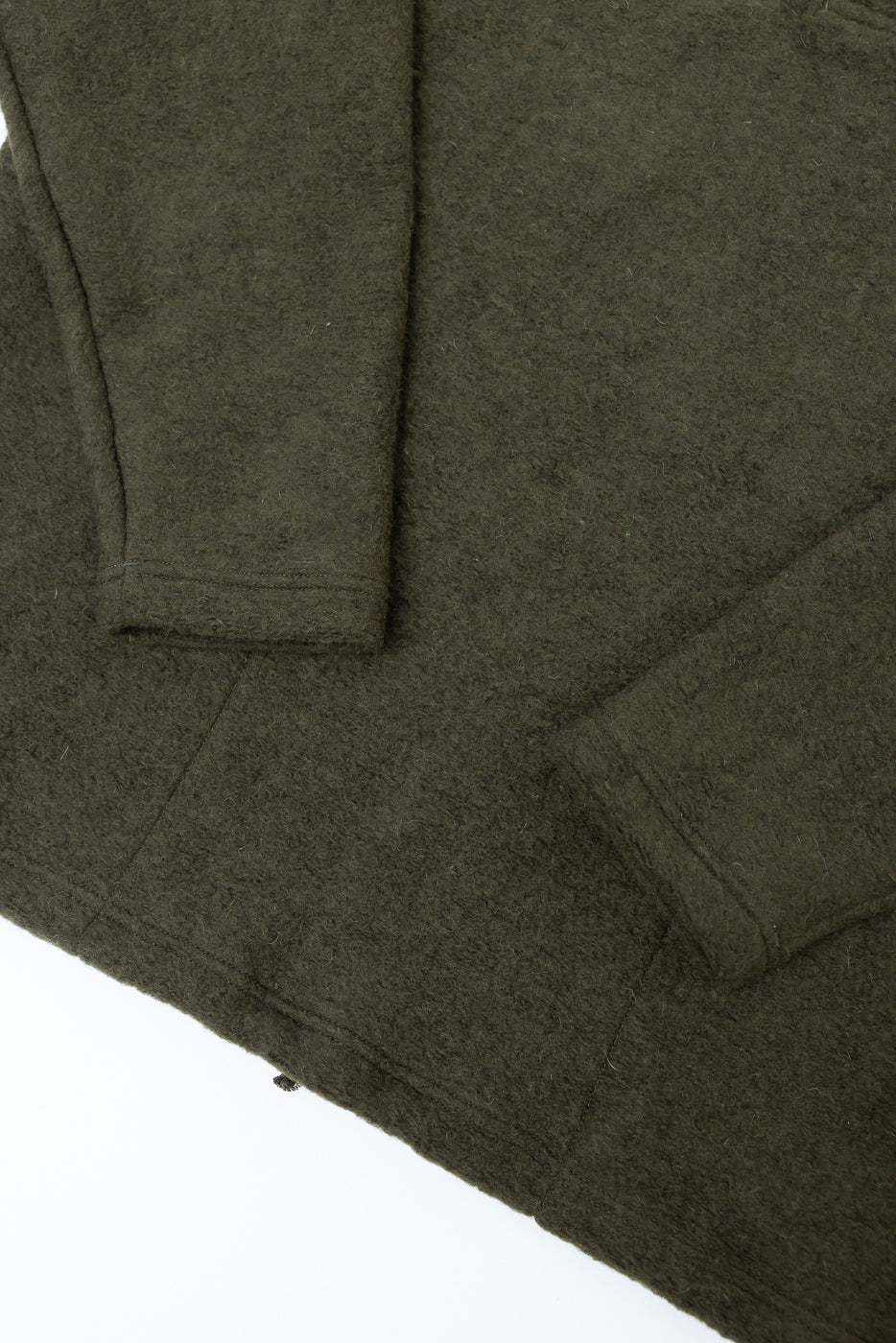 Close-up of olive wool long sleeve polo, showing fabric texture and sleeve hem, front side.
