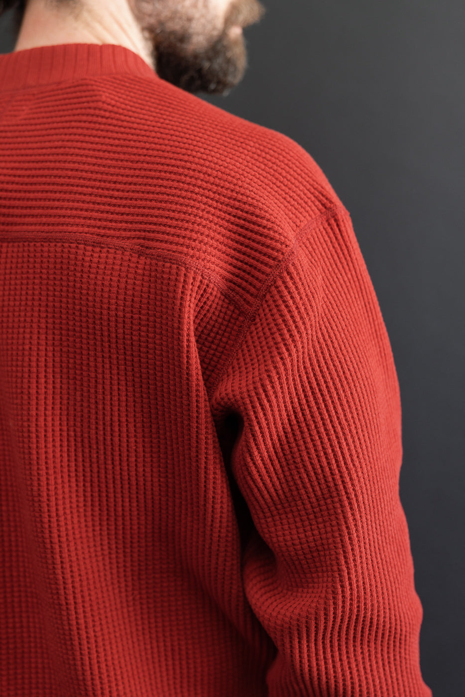 Close-up back and side view of a red waffle-knit sweater on a male model, 5'9