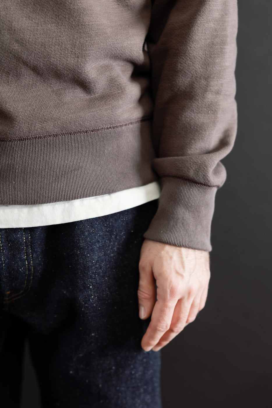 Close-up side view of a brown sweatshirt hem and sleeve on a 5'9