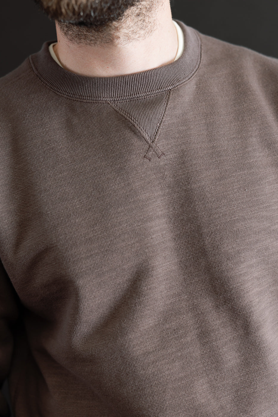 Close-up front view of a brown crewneck sweatshirt on a 5'9
