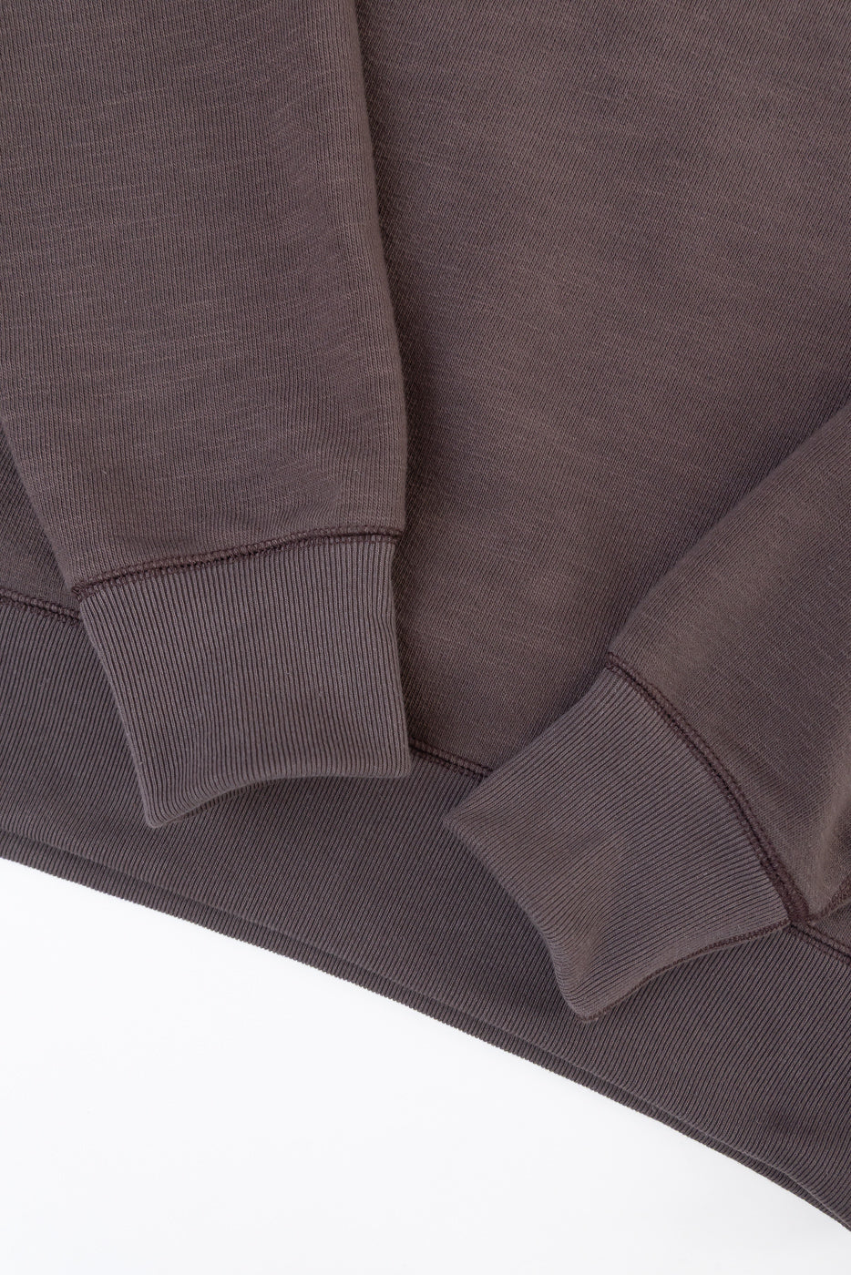 Close-up of the ribbed cuffs and hem of a dark brown sweatshirt.