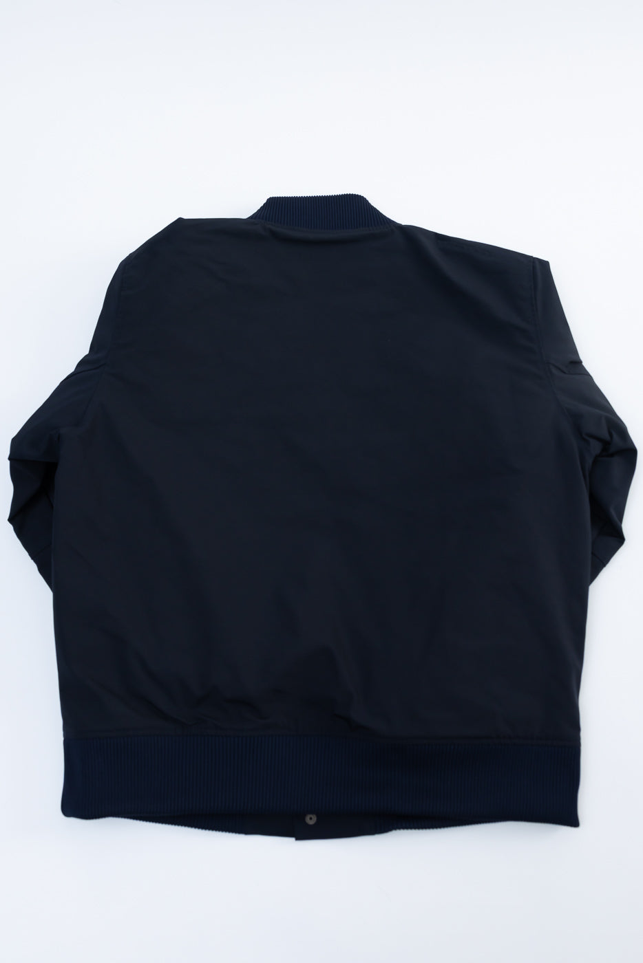 Flat lay of dark navy award jacket, back view, showing ribbed collar and hem details.