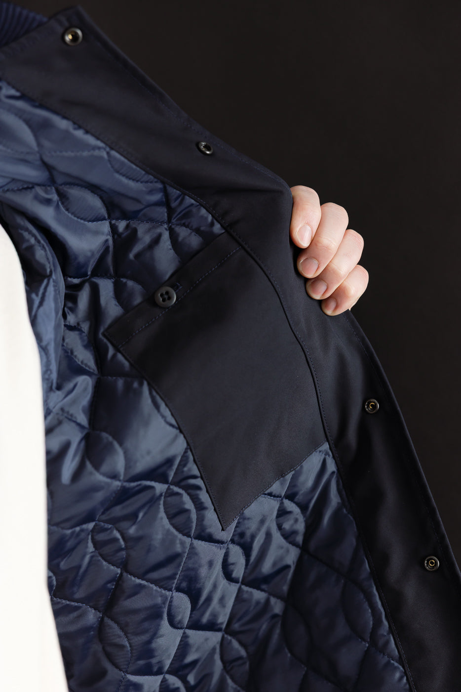 Close-up of quilted dark navy jacket interior showing buttoned inner pocket and lining details.