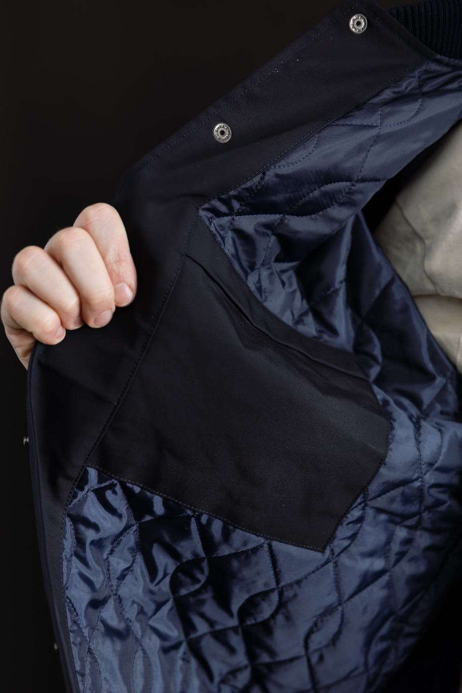 Close-up of inside left side of dark navy award jacket, showing quilted lining and interior pocket.
