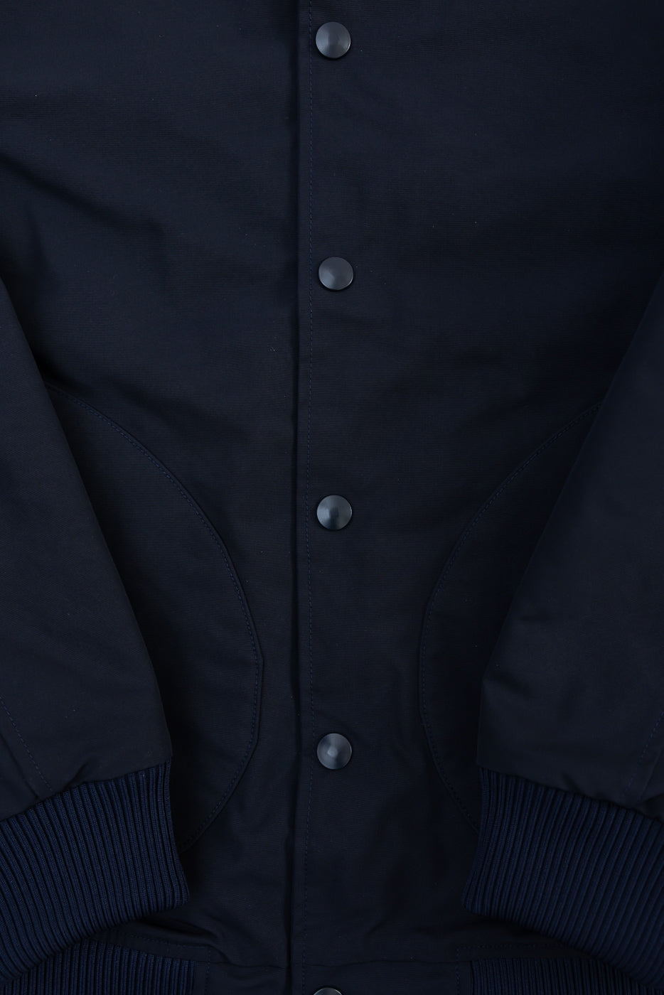 Close-up front detail of dark navy award jacket, showing snap buttons, pockets, ribbed cuffs.
