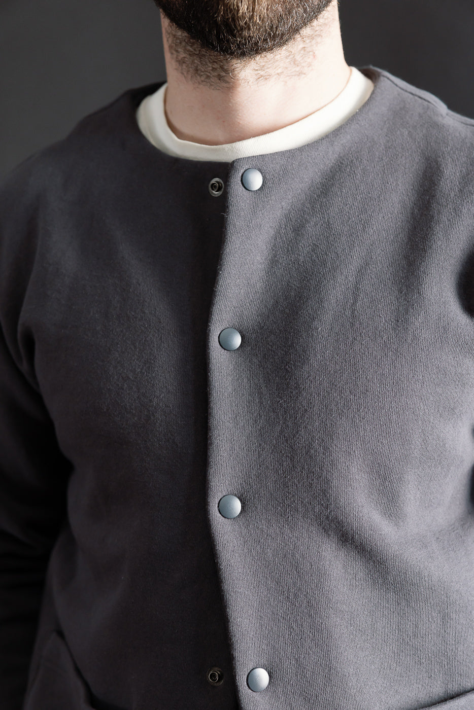 Close-up front view of Jackman Big Loop collarless jacket in ink black, snap buttons, on male model 5'9 165lbs athletic build at Dant