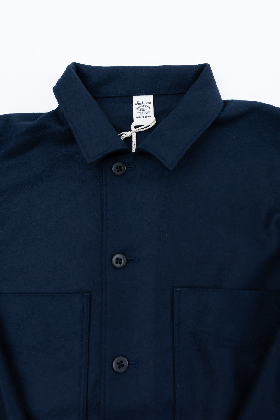 Close-up front view of navy wool button-up shirt, showing collar, buttons, chest pockets, and fabric texture.