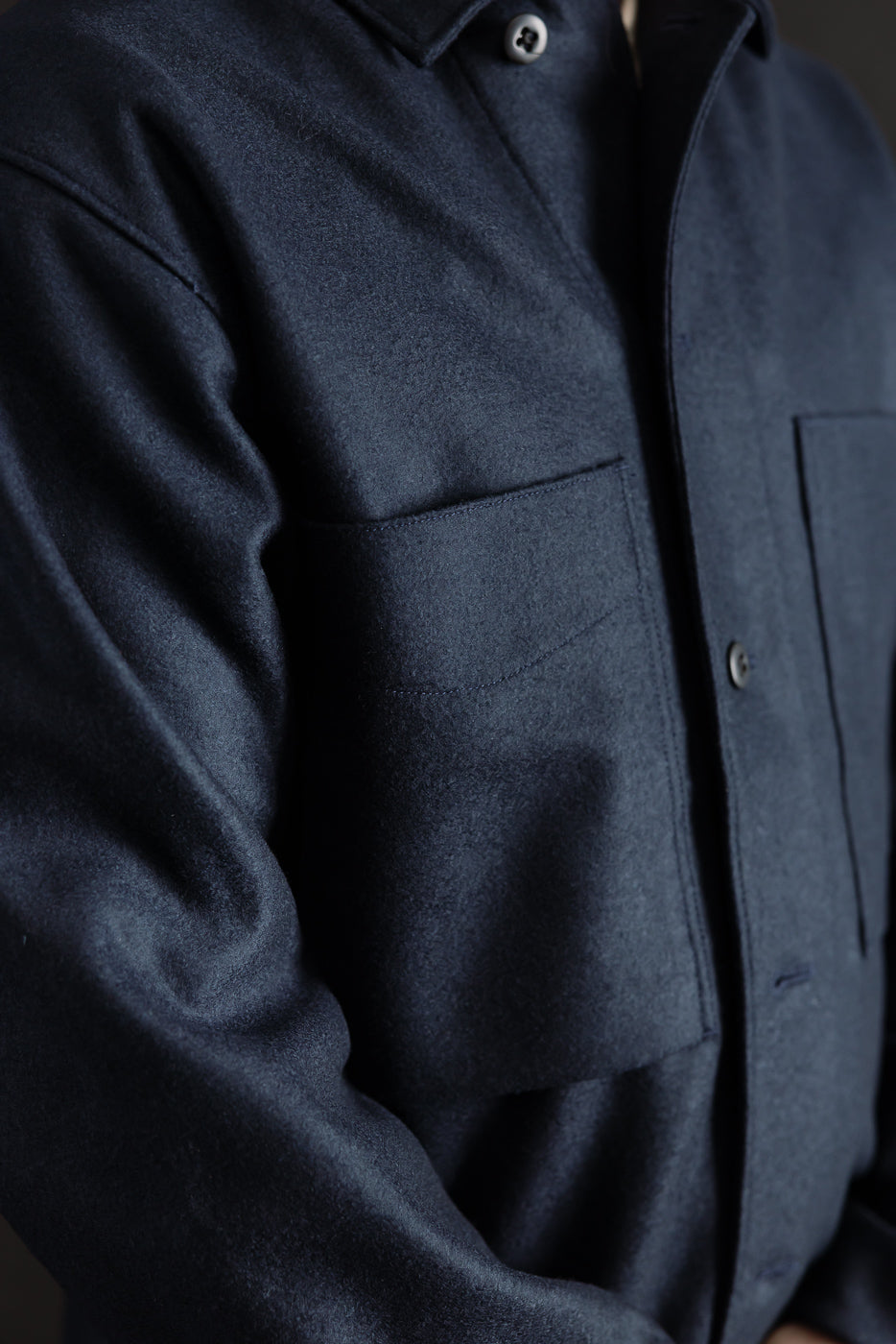 Close-up front view of men's navy wool shirt, showing collar, buttons, and chest pockets. Model is male, 5'9