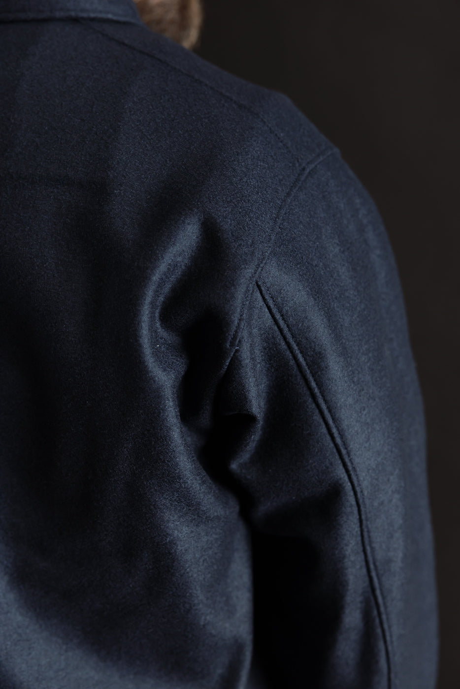 Close-up of men's navy wool shirt, right shoulder and sleeve, showing fabric texture.