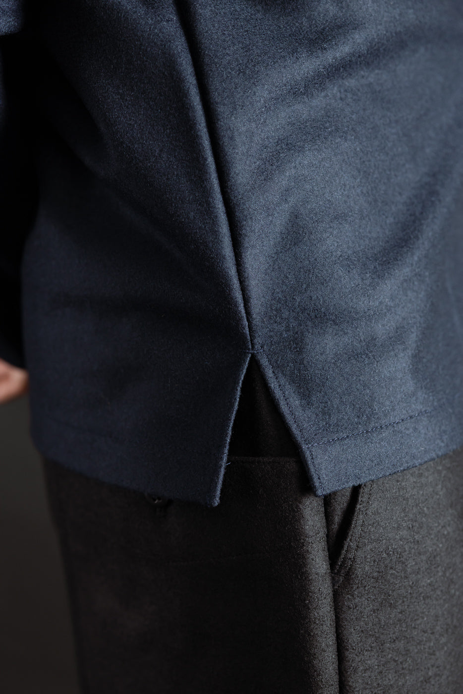 Close-up of men's navy wool shirt side hem split, fabric texture detail shown.
