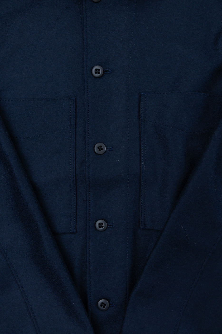 Close-up of front chest area on navy wool shirt, showing button placket and two chest pockets.