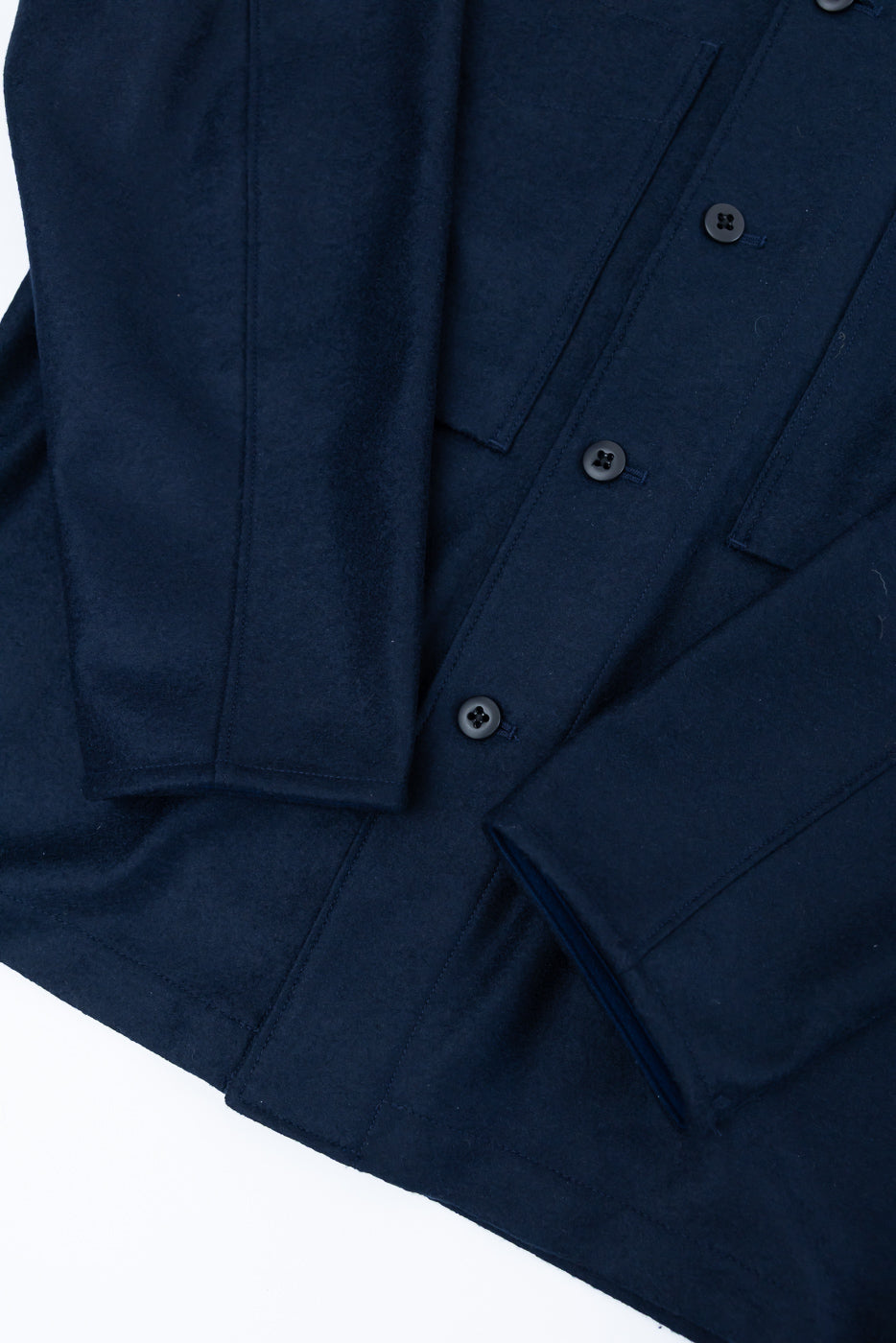 Close-up of navy wool button-up shirt, front view, showing fabric texture, cuffs, and buttons.