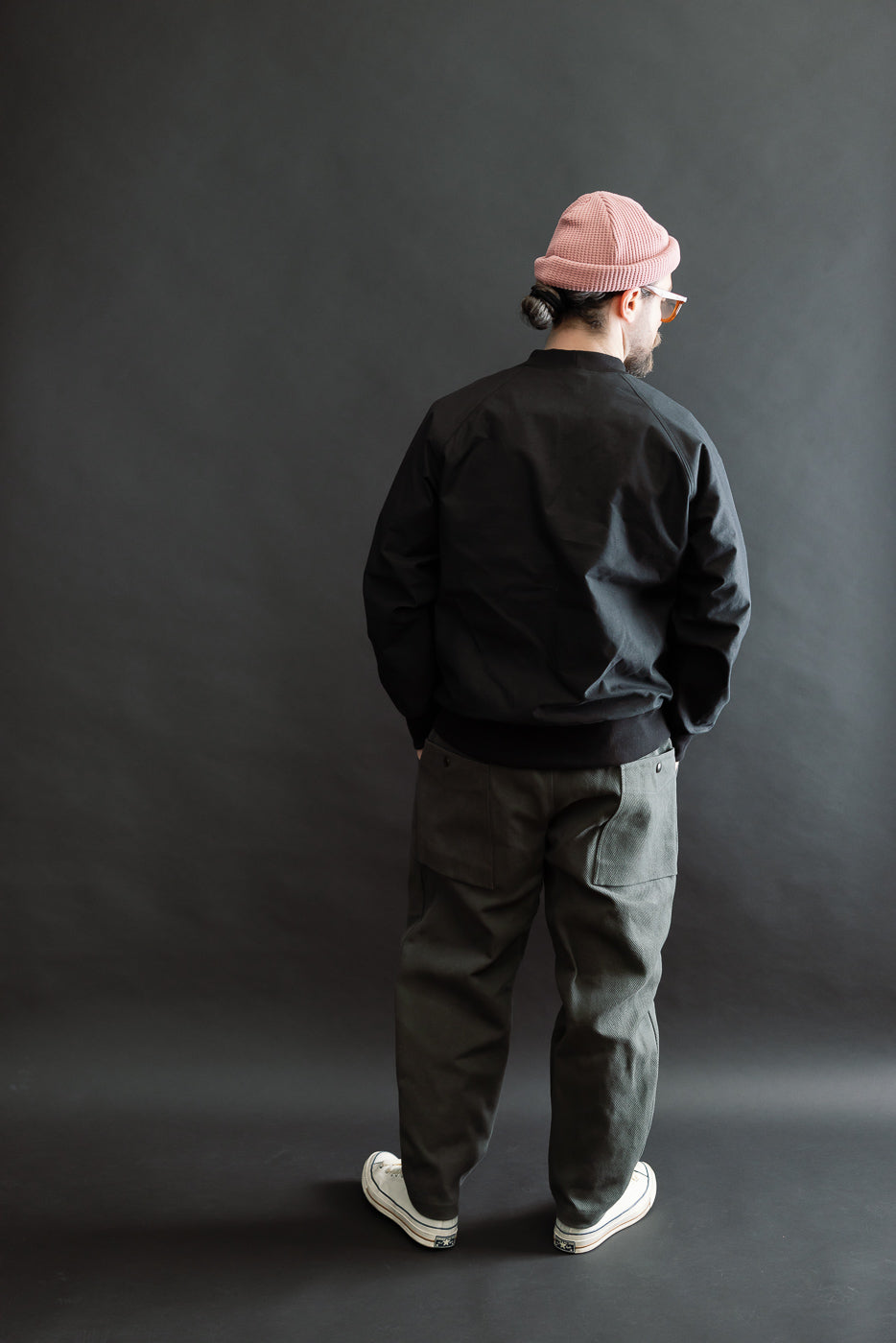 JM8615 - BN Crewneck - 07 Black seen from behind, worn by a model in a complete streetwear outfit, showcasing its voluminous, loose fit with raglan sleeves and mid-neck design.