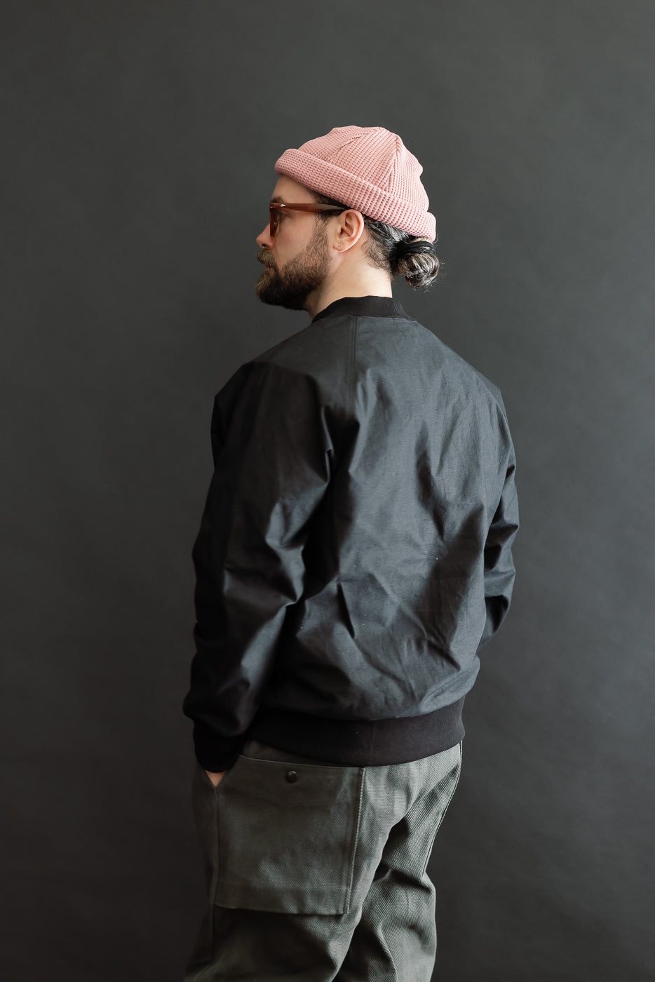 JM8615 - BN Crewneck - 07 Black showcased on a man in profile, wearing a loose bomber jacket and cargo trousers, highlighting its voluminous fit and classic raglan sleeves.