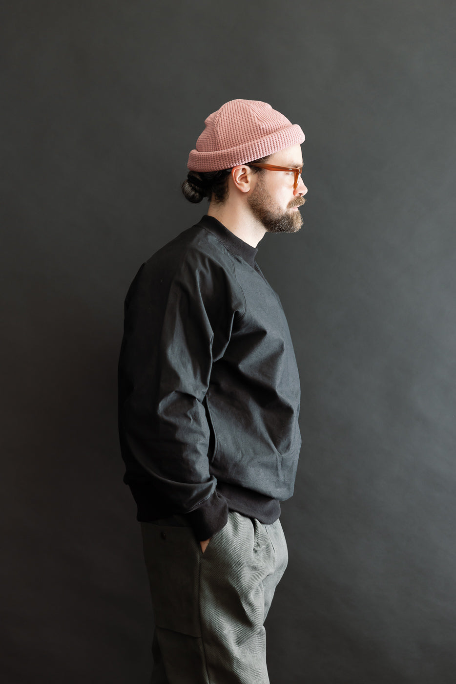 Person wearing JM8615 - BN Crewneck - 07 Black, showcasing its loose fit and classic raglan sleeves. The crewneck's texture highlights the unique nep yarn fabric, contributing to its natural, rustic appearance.