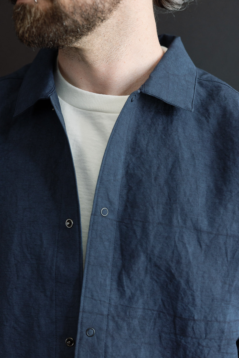Close-up front view of male model in navy shirt, showing collar, button placket, and textured fabric detail.