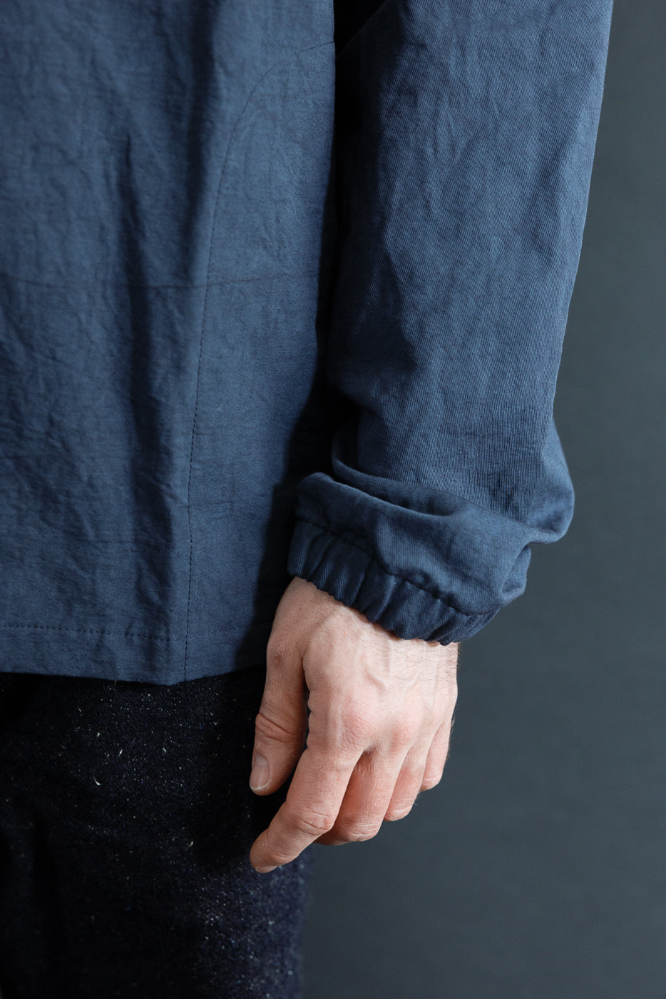 Close-up side view of navy shirt sleeve cuff on male model, 5'9