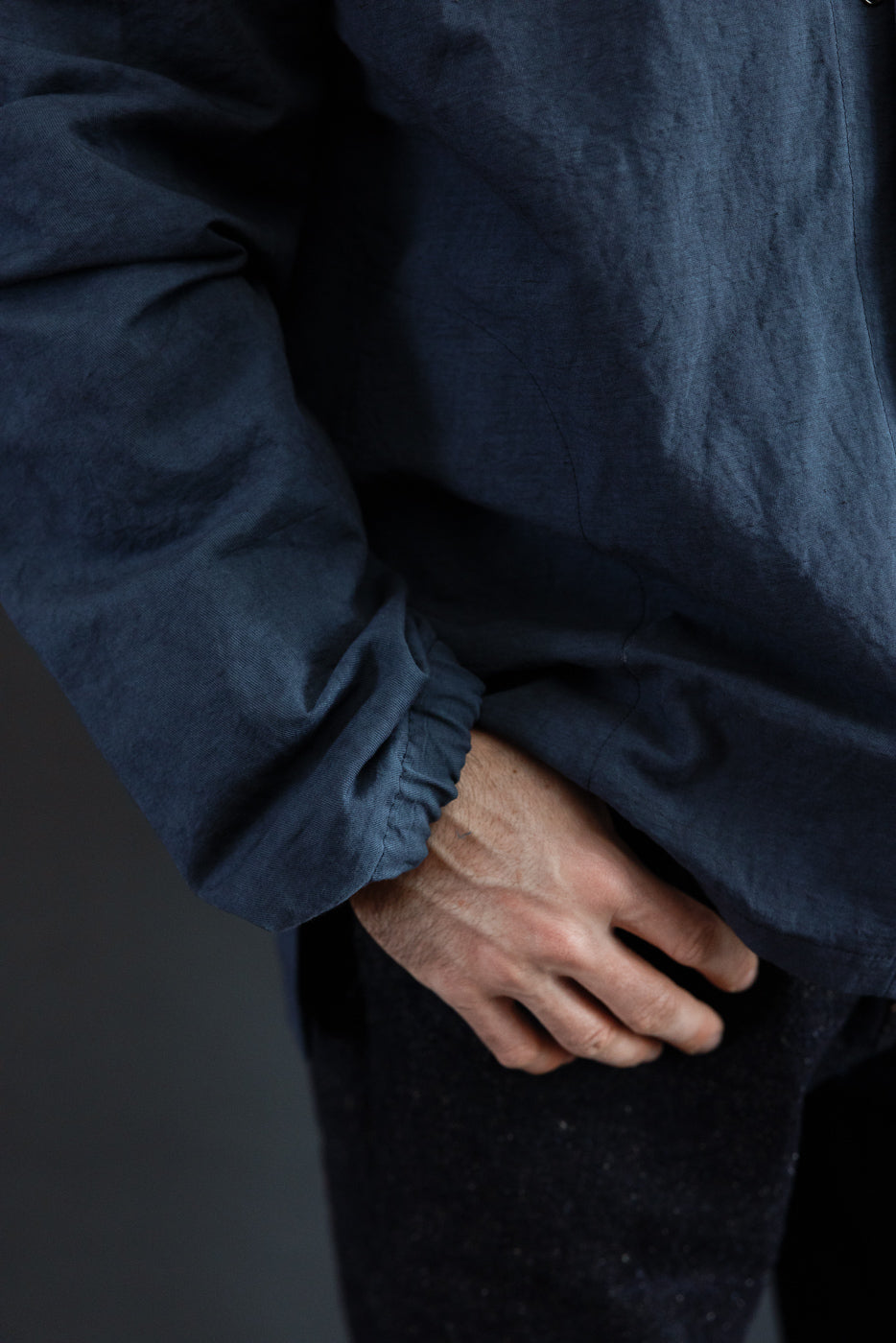 Close-up of navy shirt sleeve cuff, showing gathered hem detail on male model, 5'9