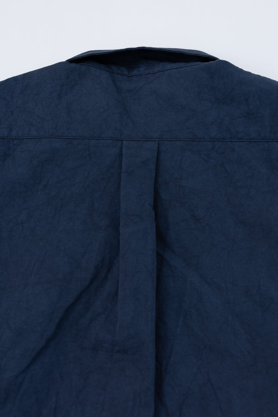 Back view close-up of navy shirt, showing collar and pleat detail, textured fabric