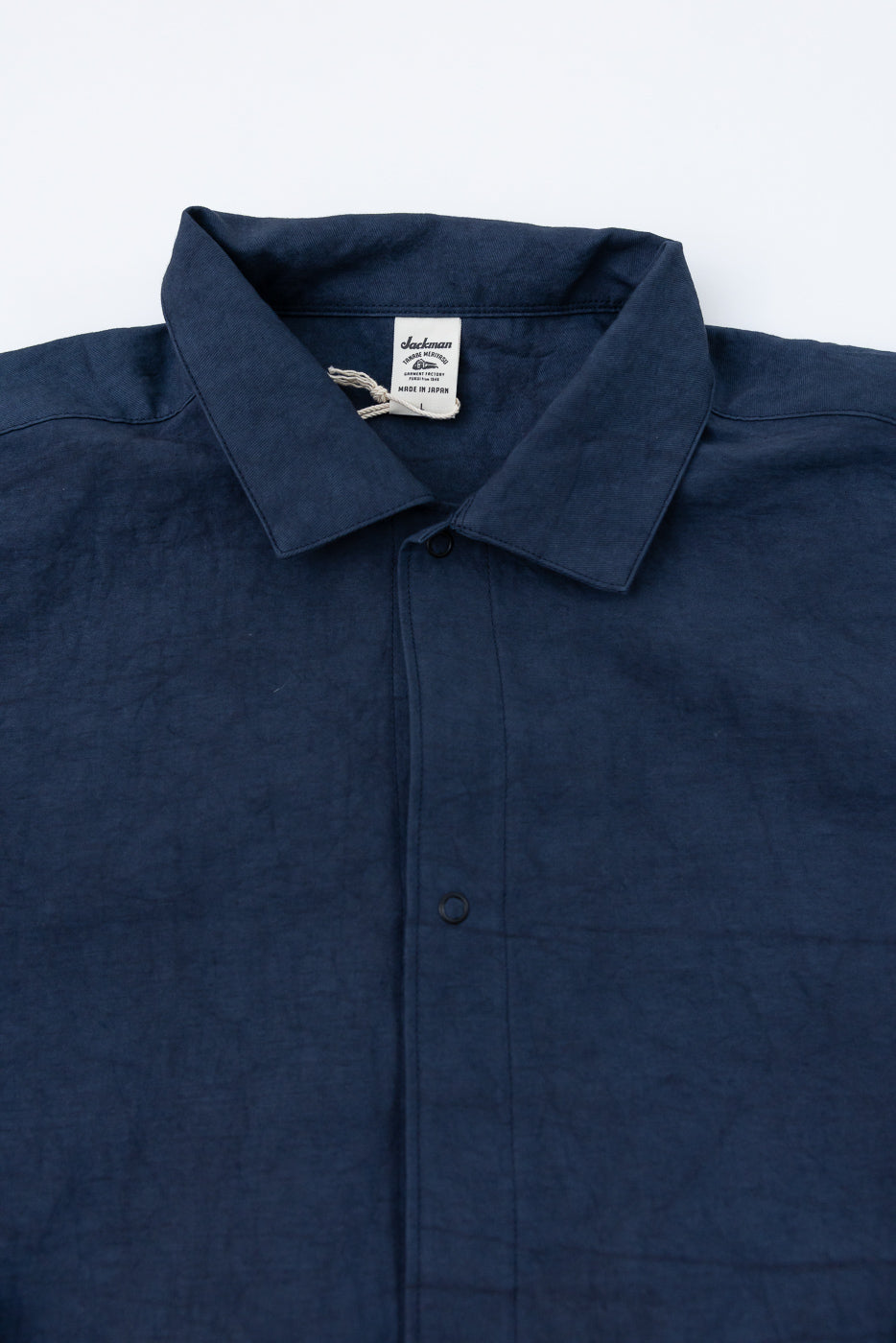 Navy blue shirt front close-up: collar, buttons, tag detail. Made in Japan, textured fabric.
