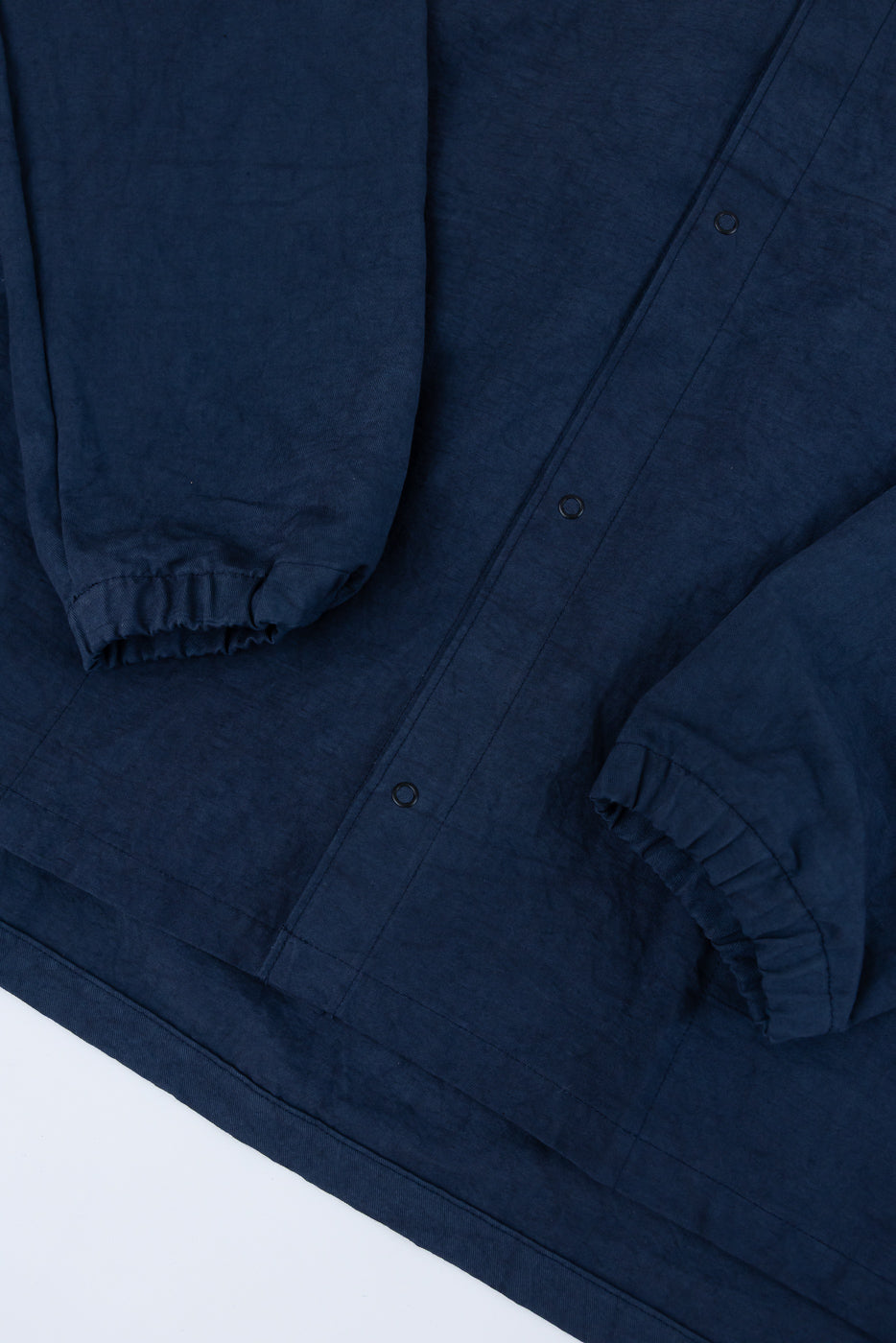 Close-up front view of navy blue shirt showing button placket, elastic sleeve cuffs, and hem detail
