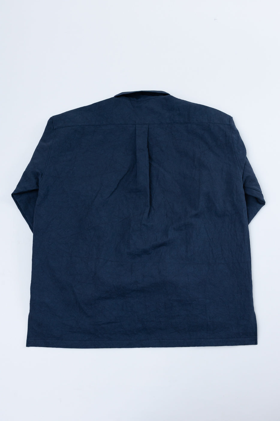 Back view of navy blue short-sleeve shirt, flat lay, showing pleat detail at yoke and clean hem