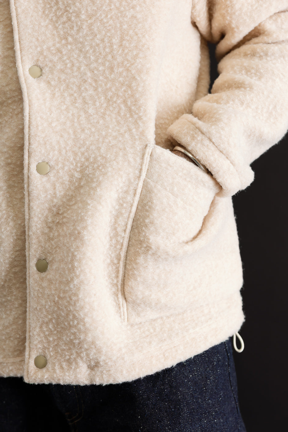 Close-up front view of a male model wearing a cream sherpa fleece jacket, showing button details and texture.