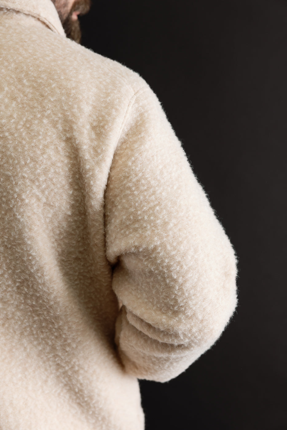 Close-up of the back and sleeve of a cream fleece jacket on a male model, 5'9