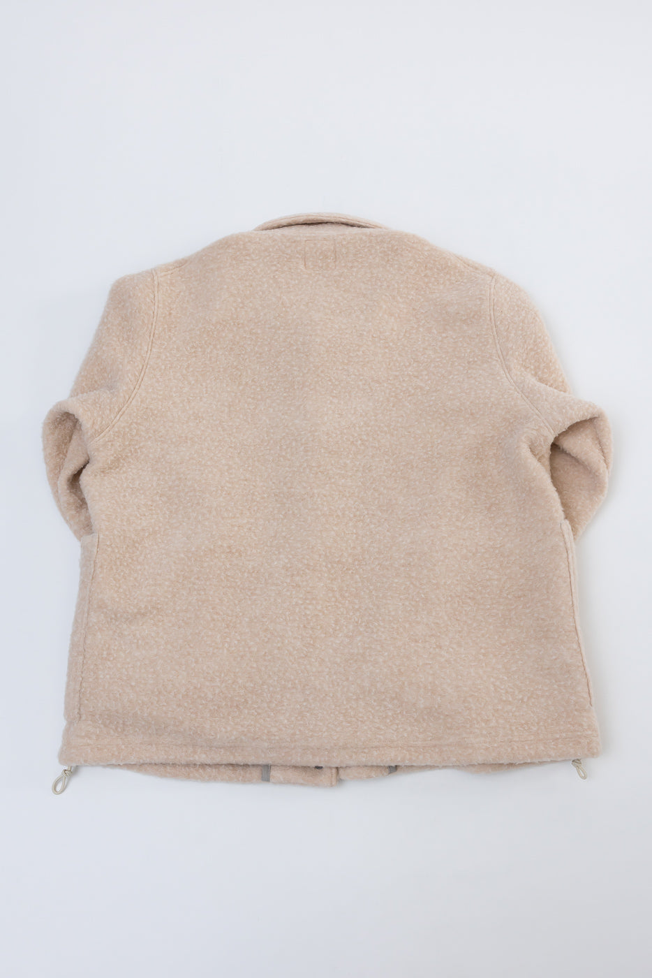 Flat lay of the back of a beige fleece jacket showing the textured fabric.