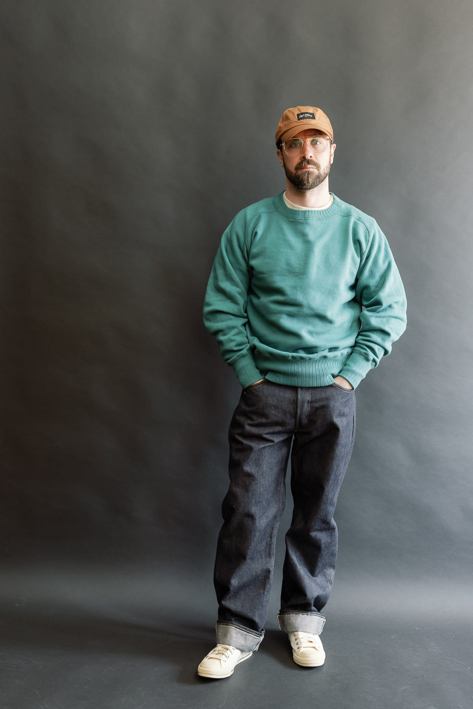 JG-CS24 - The Albert Sweat - Blue Green worn by a 5'9 Caucasian male, styled with dark cuffed jeans and white sneakers, showcasing its casual fit and heritage-inspired design from Dant's curated collection.