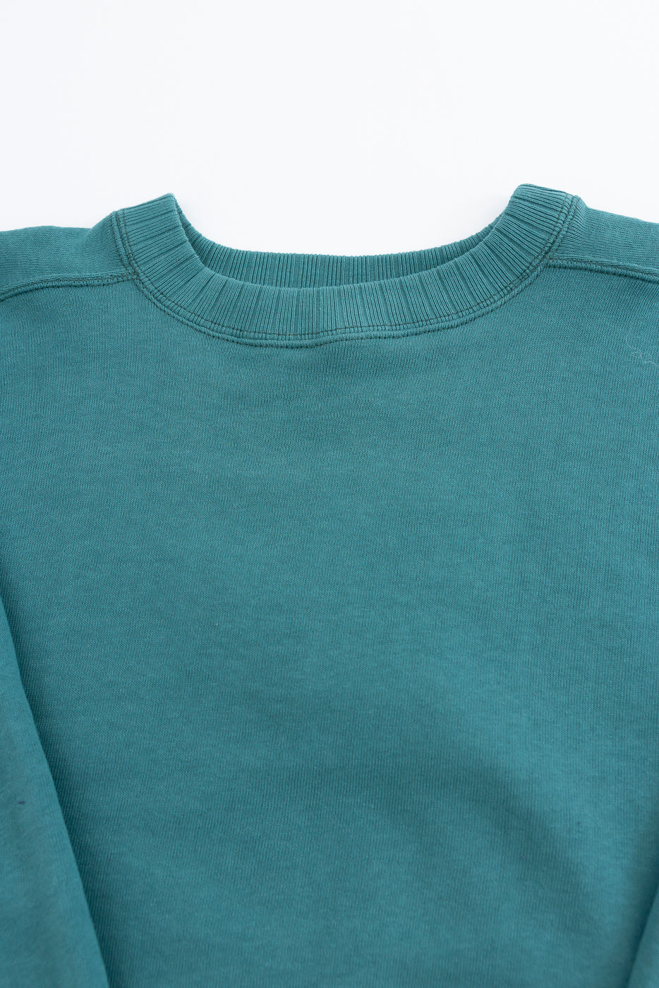 JG-CS24 - The Albert Sweat - Blue Green: Teal crewneck sweatshirt, showcasing ribbed collar and torso. Circular knit, 100% cotton, with freedom sleeves for ease of movement and a drape-enhancing seamless design.