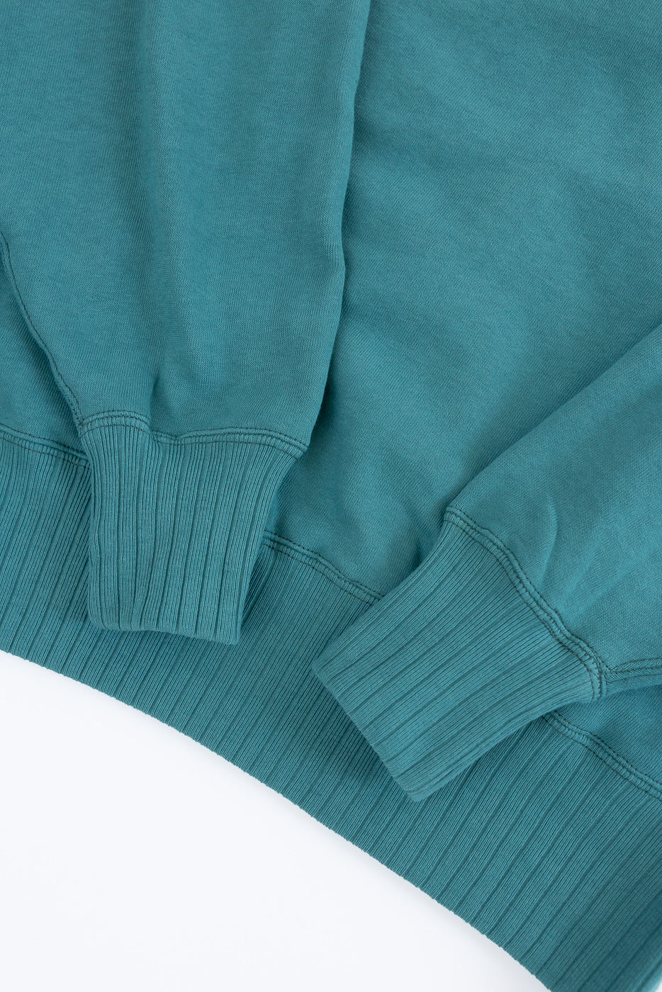 Close-up of the JG-CS24 - The Albert Sweat - Blue Green sweatshirt's ribbed cuffs and hem, showcasing its plush, soft-knit texture and seamless, circular-knit construction reflecting vintage sportswear design.