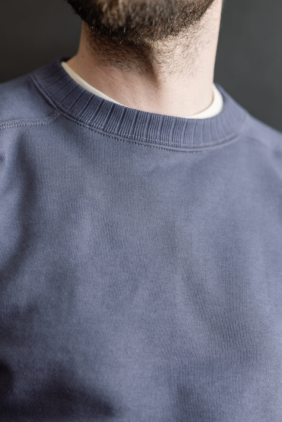JG-CS24 - The Albert Sweat - Eggplant features a close-up of its crewneck design and soft, plush texture, displayed on a model with short, dark facial hair, embodying heritage-inspired menswear style.