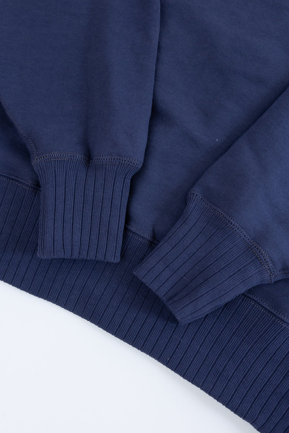 Close-up of the JG-CS24 Albert Sweat in navy-blue, showcasing rib-knit cuffs and hem, circular knit construction, and freedom sleeve design, inspired by 1940s sportswear from John Gluckow's archive.