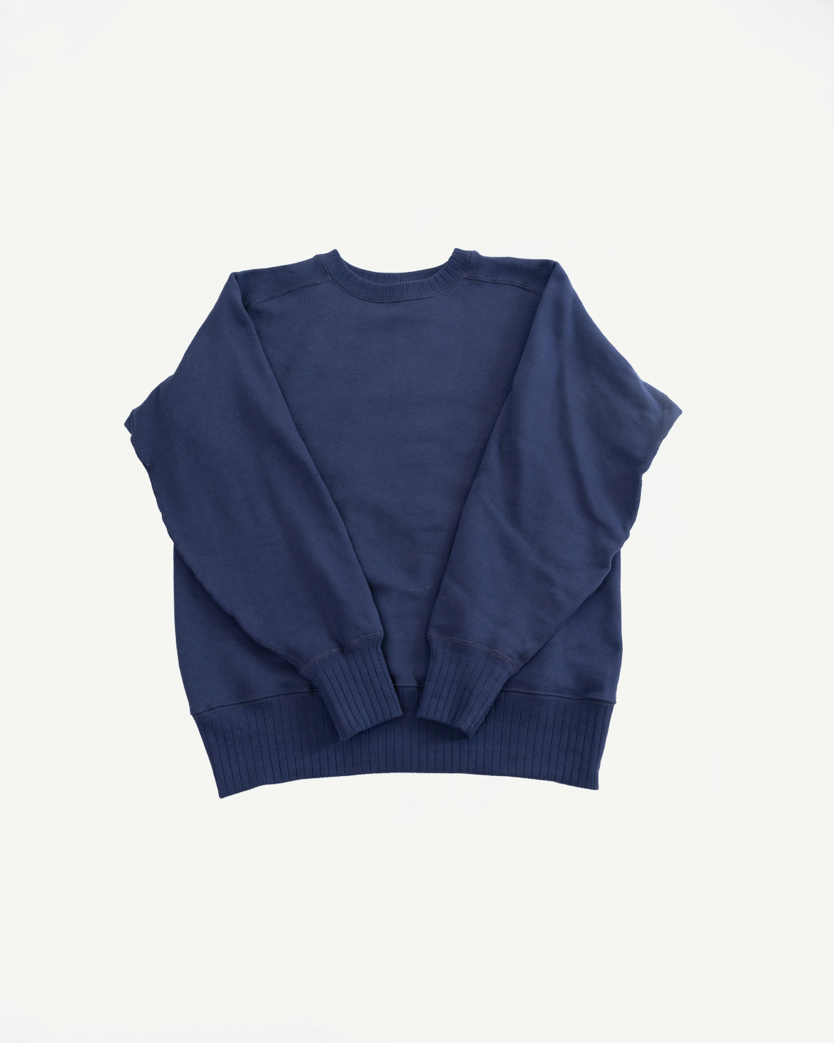 The John Gluckow JG-CS24 Albert Sweat, a vintage-inspired navy-blue crewneck sweatshirt, showcases a seamless, circular knit design with freedom sleeves, epitomizing heritage craftsmanship for a relaxed, timeless look.