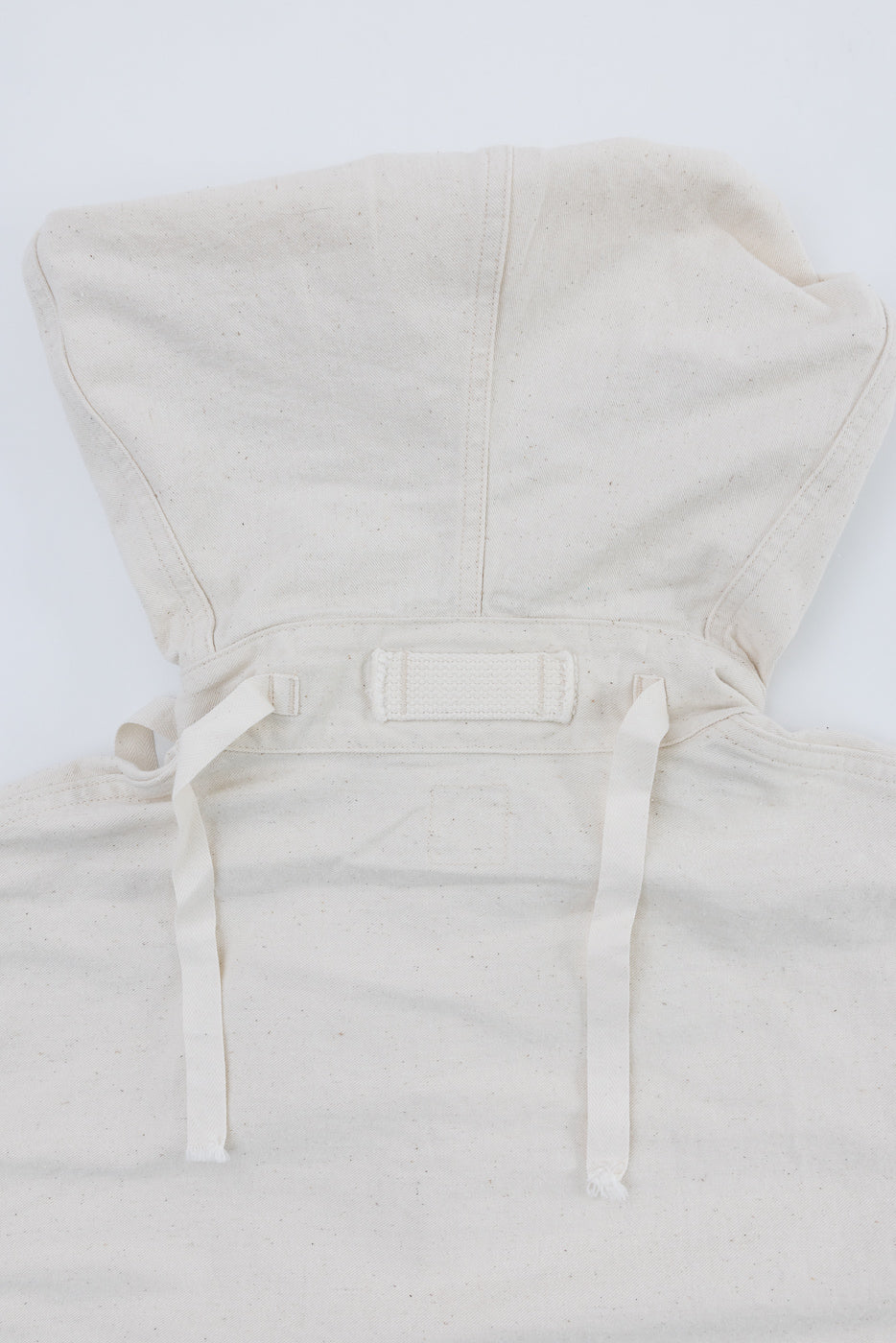 Close-up of off-white parka hood, back view, showing drawstrings and fabric texture.