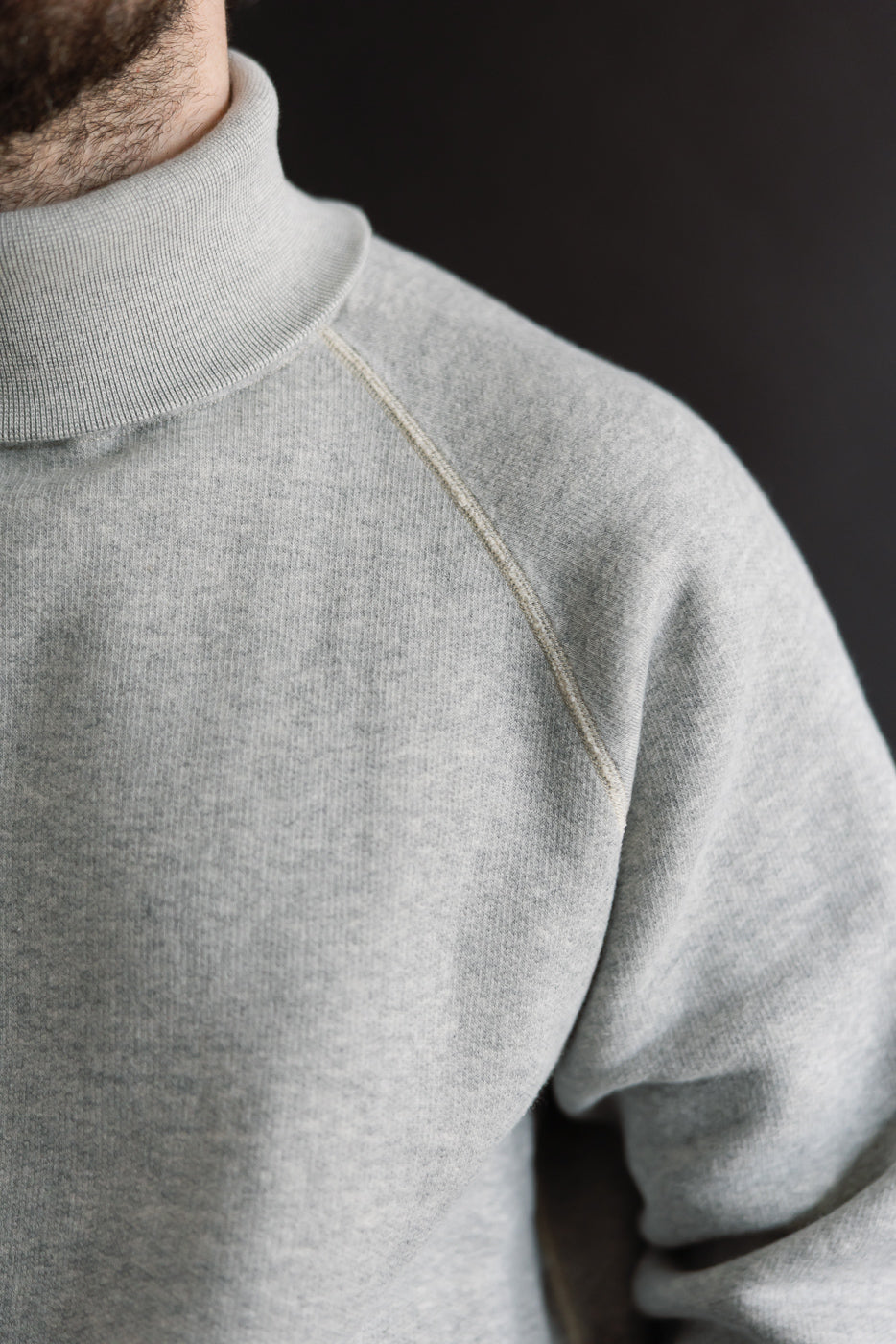 Close-up of front left shoulder and turtleneck on male model, athletic build, wearing grey Loop & Weft super fluffy knit raglan turtleneck at Dant.