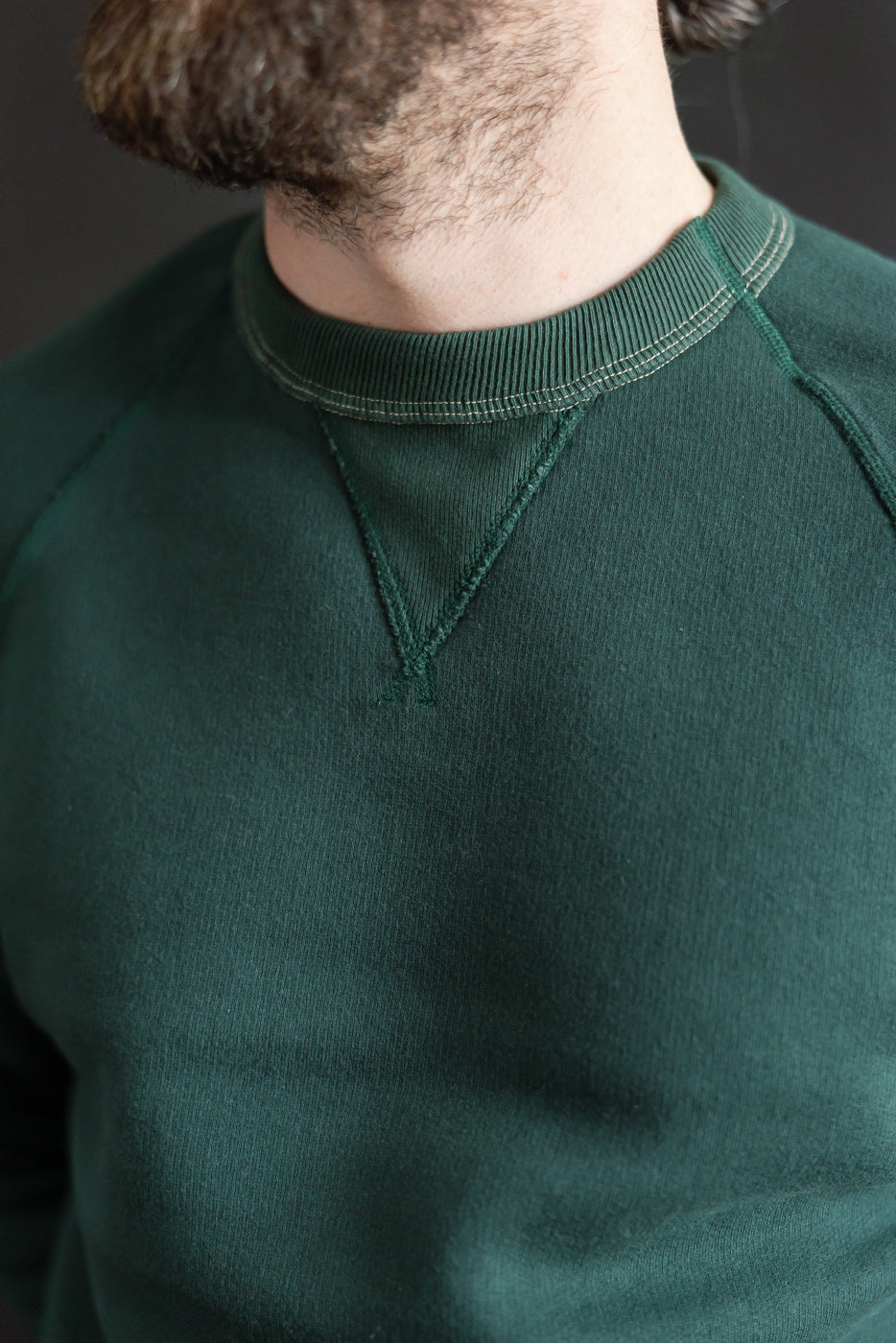 Close-up front detail of Loop & Weft super fluffy knit forest green crewneck, V-gusset collar on male model, 5'9