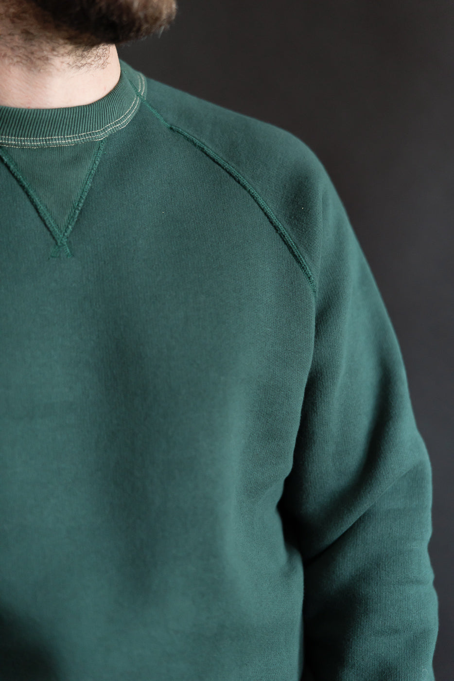 Close-up of Loop & Weft forest green crew neck sweatshirt front, V-gusset, raglan sleeve, modeled on 5'9